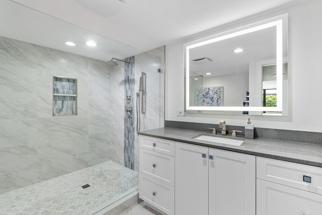 bathroom with vanity and a tile shower