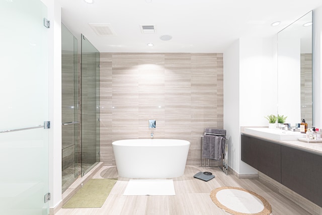 bathroom featuring tile patterned flooring, vanity, tile walls, and shower with separate bathtub