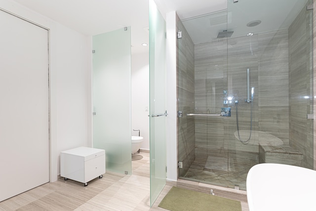 bathroom featuring toilet, tile patterned floors, and a shower with door