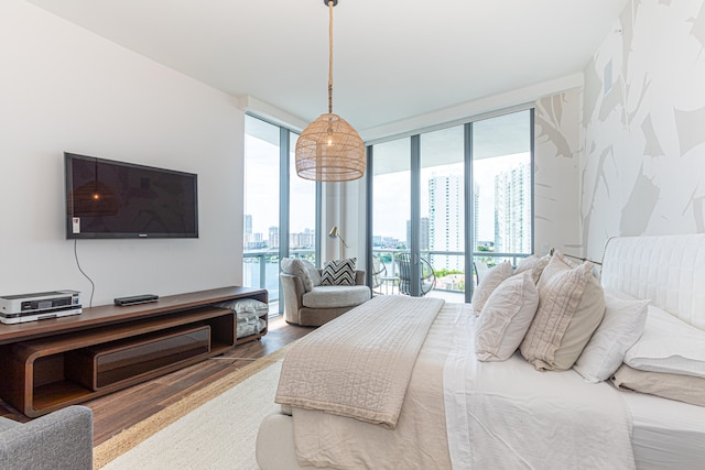 bedroom featuring hardwood / wood-style floors, access to exterior, and a wall of windows