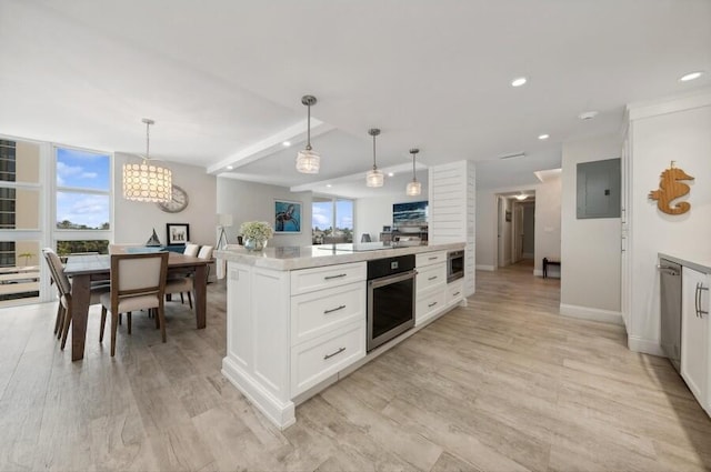 kitchen with appliances with stainless steel finishes, hanging light fixtures, light wood-type flooring, and white cabinetry