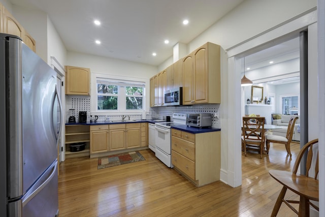 kitchen featuring stainless steel appliances, light brown cabinetry, dark countertops, and light wood-style floors