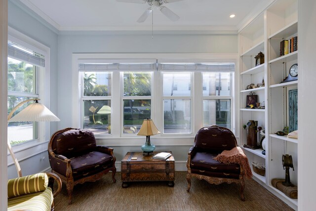 sitting room with ceiling fan, ornamental molding, built in features, and a healthy amount of sunlight