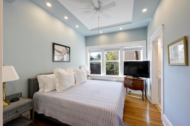 bedroom featuring ceiling fan, hardwood / wood-style flooring, and a tray ceiling