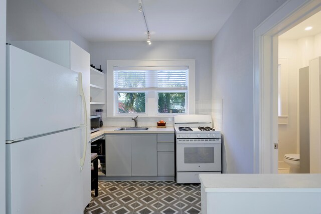 kitchen featuring white appliances, sink, dark tile patterned floors, gray cabinetry, and rail lighting