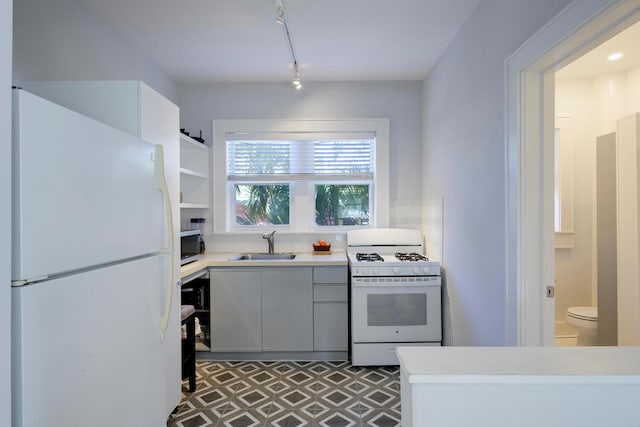 kitchen with white appliances, light countertops, a sink, and open shelves