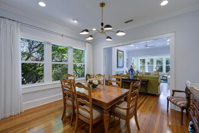 dining space with a chandelier, crown molding, hardwood / wood-style flooring, and a healthy amount of sunlight