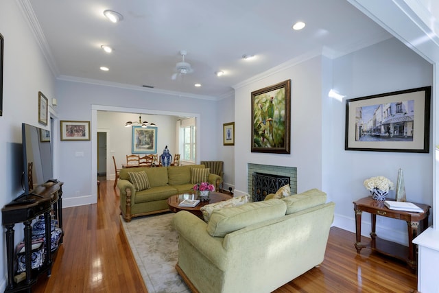 living room featuring hardwood / wood-style floors, crown molding, a fireplace, and ceiling fan