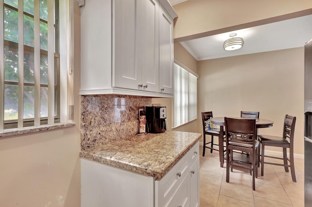 kitchen featuring light tile floors, ornamental molding, white cabinets, light stone countertops, and tasteful backsplash