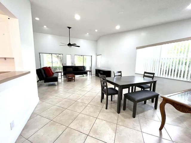 dining room with a high ceiling, ceiling fan, and light tile flooring