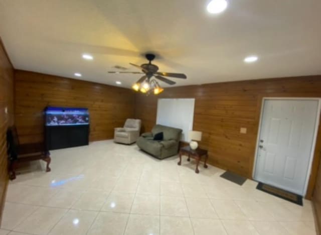 tiled living room featuring wood walls and ceiling fan