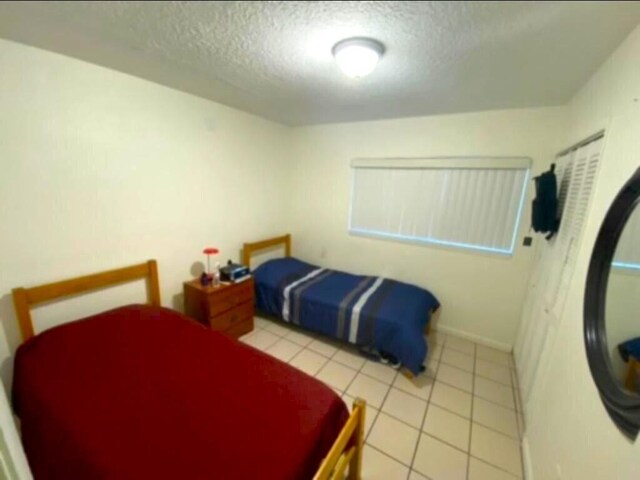 tiled bedroom with a textured ceiling