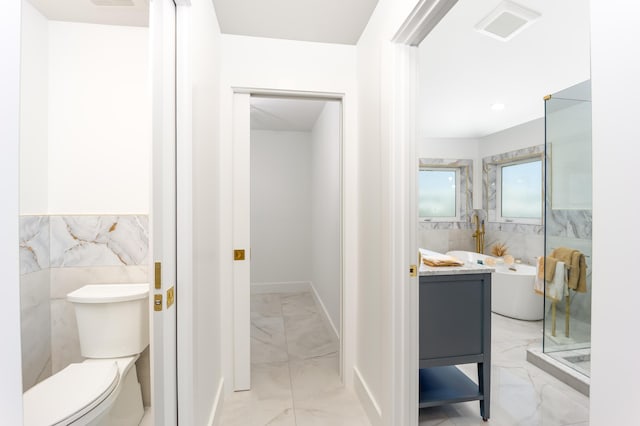 bathroom with a bathtub, tile walls, toilet, and vanity