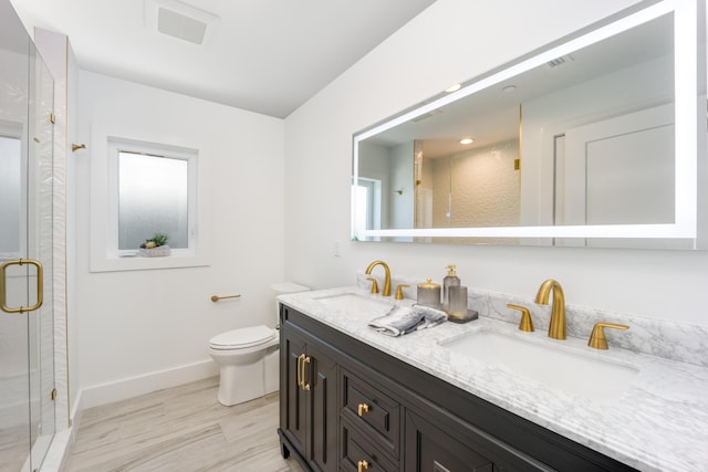 bathroom featuring vanity, a shower with shower door, and toilet