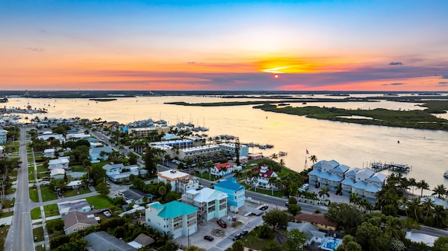 aerial view at dusk featuring a water view