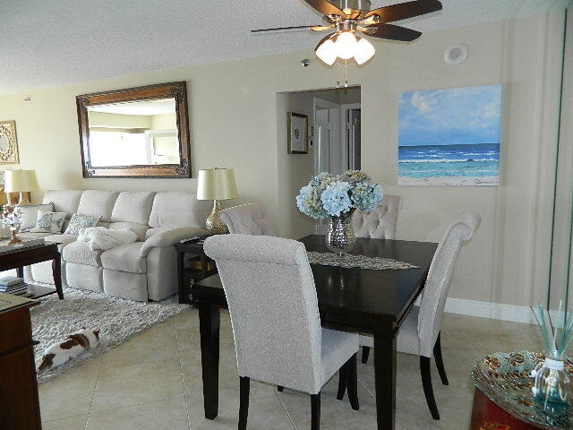 dining room with ceiling fan, baseboards, a textured ceiling, and light tile patterned flooring