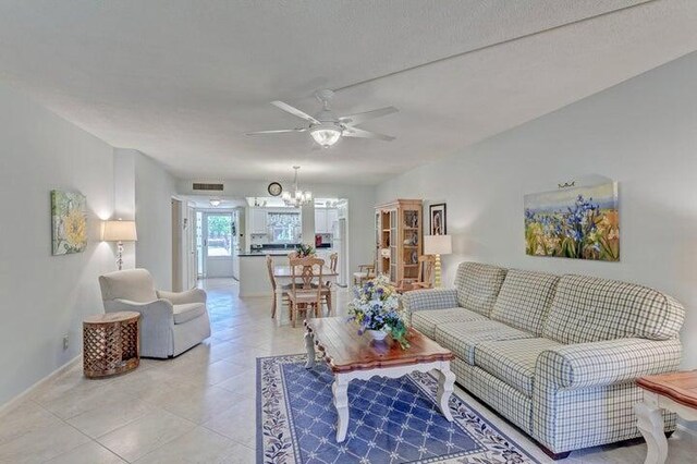 living room featuring ceiling fan with notable chandelier and light tile patterned flooring