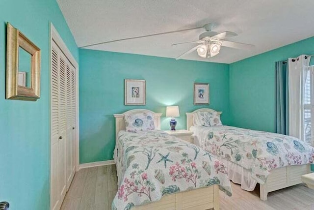 bedroom with a closet, ceiling fan, light hardwood / wood-style flooring, and a textured ceiling