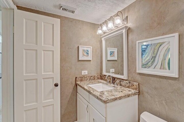 bathroom with vanity, toilet, and a textured ceiling