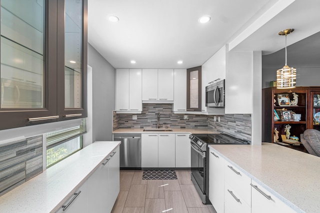 kitchen with appliances with stainless steel finishes, tasteful backsplash, light stone counters, sink, and white cabinets