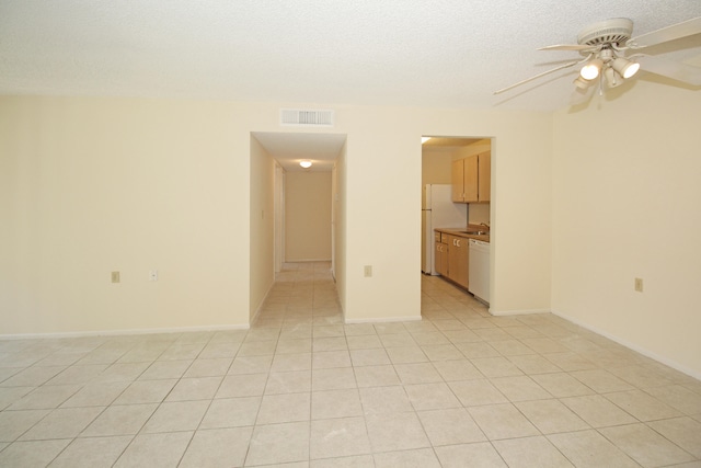 interior space with light tile floors, ceiling fan, a textured ceiling, and sink