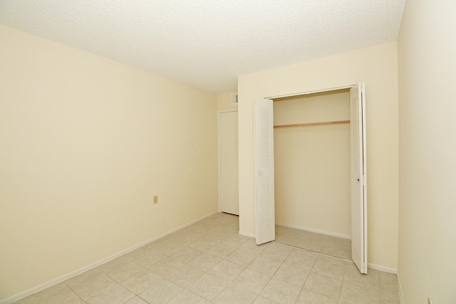 unfurnished bedroom with a closet, light tile floors, and a textured ceiling