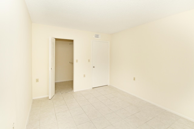 interior space with light tile flooring, a closet, and a textured ceiling