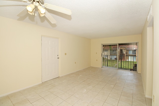 empty room with light tile floors, ceiling fan, and a textured ceiling