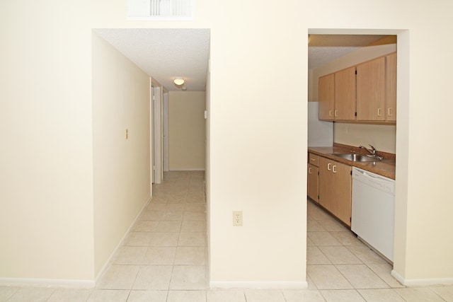 hall with a textured ceiling, light tile flooring, and sink