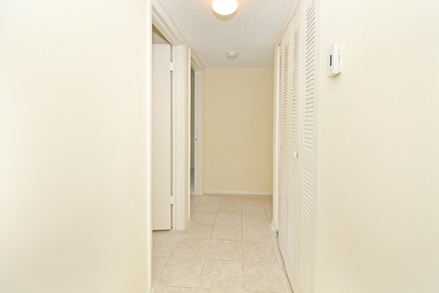 hall featuring a textured ceiling and light tile floors