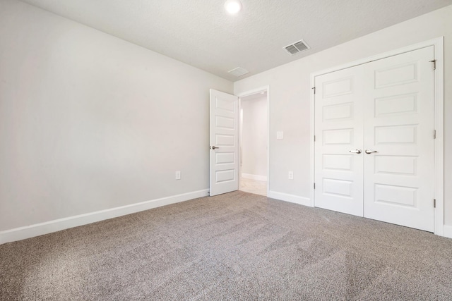 unfurnished bedroom featuring carpet flooring, a closet, and a textured ceiling