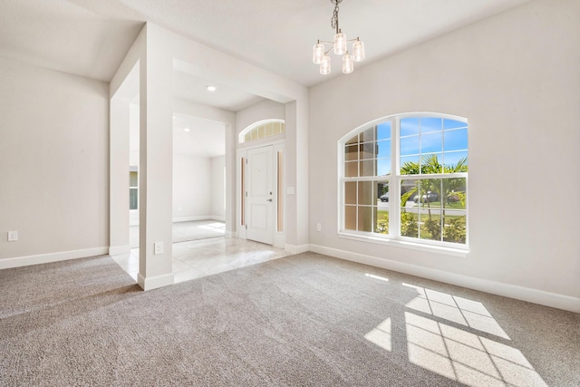 carpeted empty room featuring an inviting chandelier