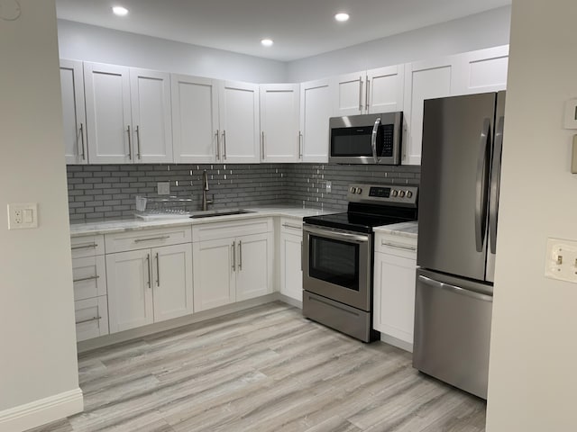 kitchen featuring tasteful backsplash, white cabinetry, sink, and appliances with stainless steel finishes