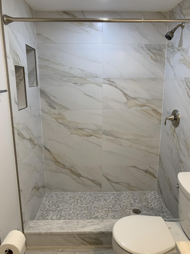 bathroom with toilet and a tile shower