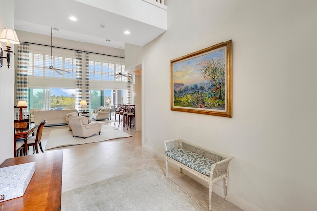 hall featuring light tile floors and a high ceiling