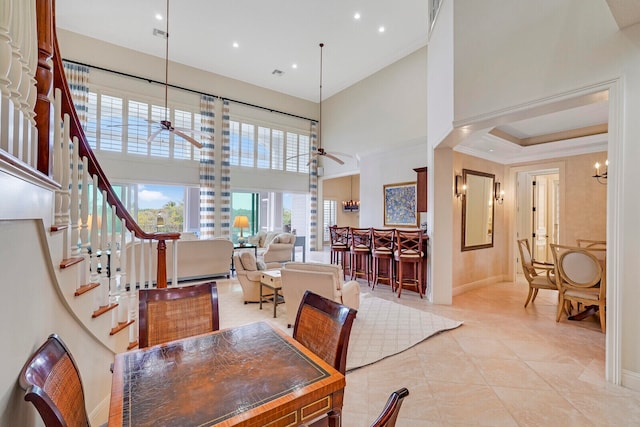 tiled dining space with ceiling fan with notable chandelier and a high ceiling