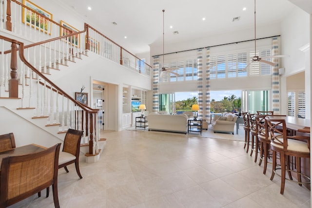 interior space featuring a high ceiling, light tile patterned floors, ceiling fan, and built in shelves