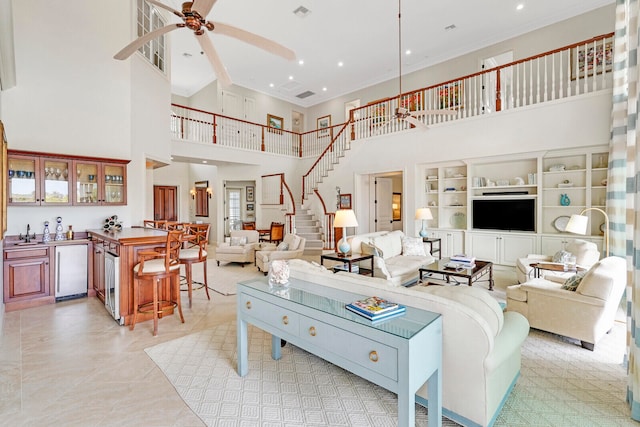 living room with ceiling fan, light tile flooring, sink, a towering ceiling, and ornamental molding