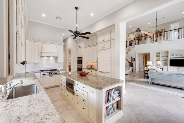 kitchen with light stone countertops, ceiling fan, appliances with stainless steel finishes, sink, and custom range hood