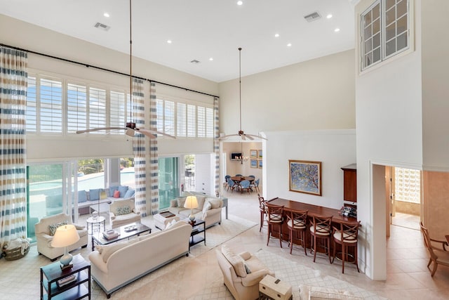 living room with ceiling fan, light tile floors, and a towering ceiling