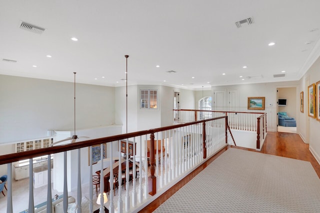 hall with ornamental molding and light hardwood / wood-style floors