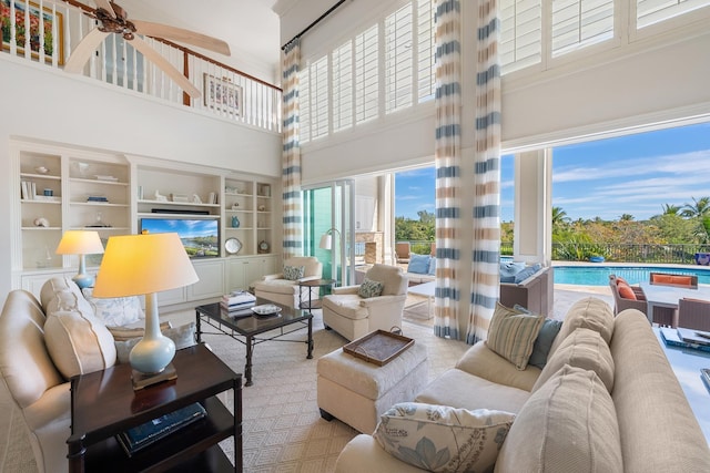 living room with ceiling fan, built in features, and a high ceiling