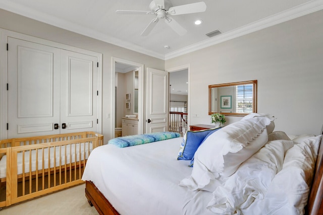 carpeted bedroom featuring a closet, connected bathroom, ornamental molding, and ceiling fan