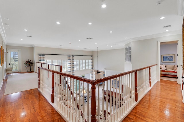 corridor featuring ornamental molding, a wealth of natural light, and light wood-type flooring