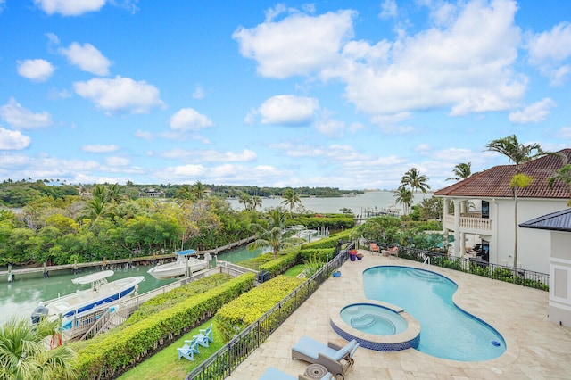 view of pool featuring an in ground hot tub, a water view, and a patio area