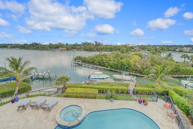 view of swimming pool with a dock, a water view, and a patio