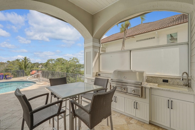 view of patio featuring area for grilling, grilling area, a fenced in pool, and sink