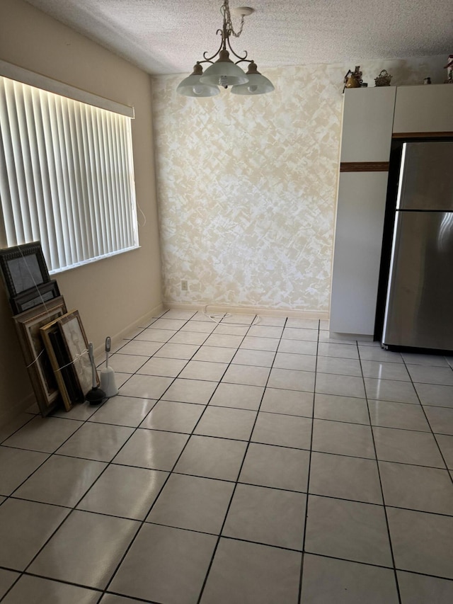 interior space featuring a textured ceiling, a notable chandelier, and light tile patterned flooring