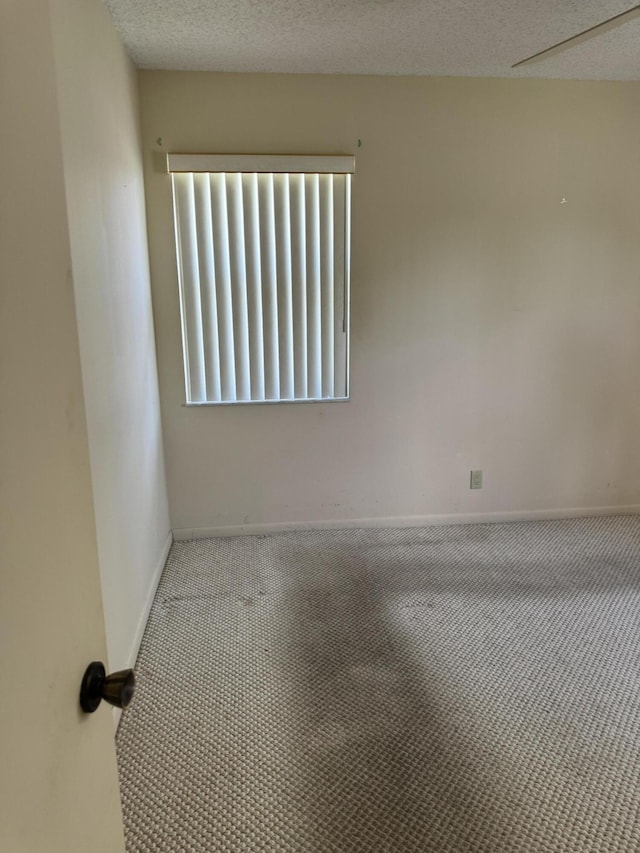 carpeted empty room featuring a textured ceiling