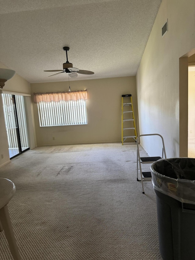 spare room featuring a textured ceiling, light colored carpet, and ceiling fan